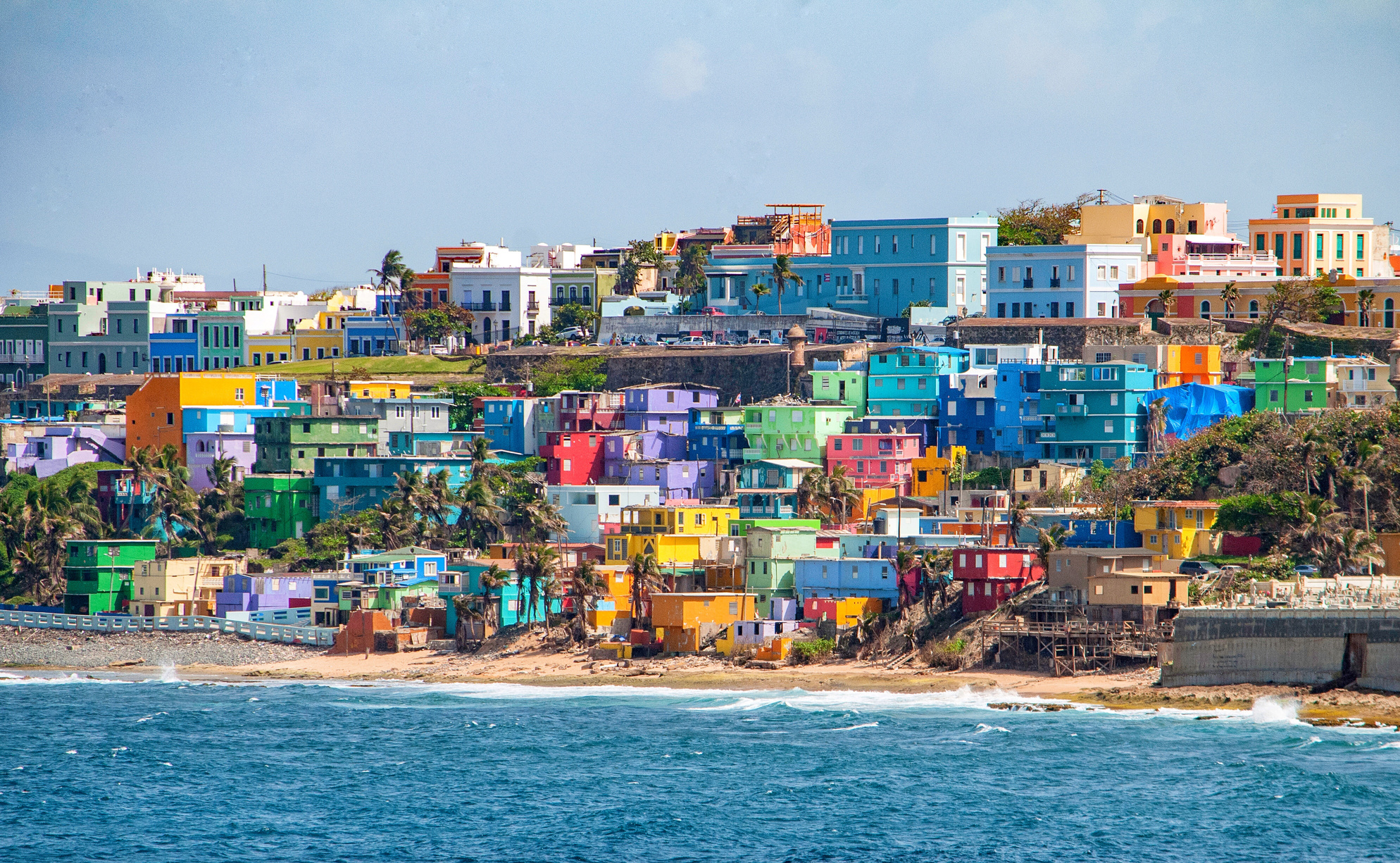 Bright colorful houses line the hills overlooking the beach in San Juan, Puerto Rico